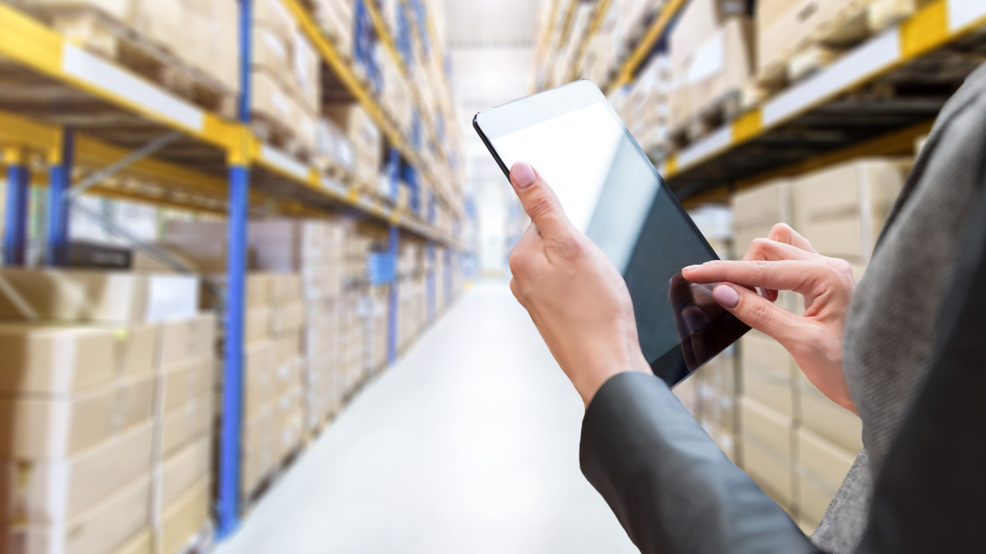 Warehouse aisle with a professional using a tablet